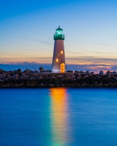 A beautiful lighthouse standing tall on a calm coastline at dawn, casting a steady beacon of light across the water, symbolizing spiritual intimacy and an inner peace that brings hope and healing to the world.