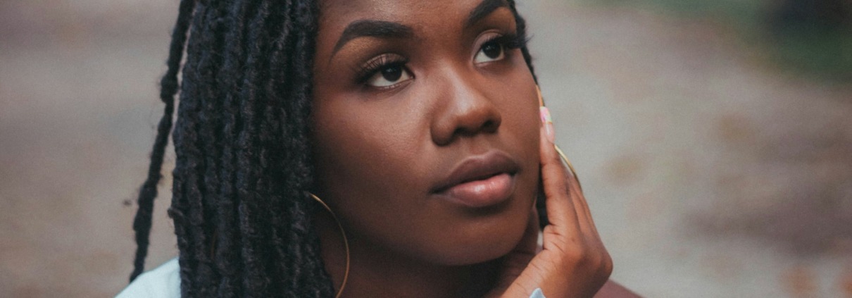 Close-up portrait of a contemplative young Black woman looking upward in quiet reflection, symbolizing deep emotional healing, vulnerability, and inner peace.