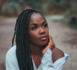 Close-up portrait of a contemplative young Black woman looking upward in quiet reflection.