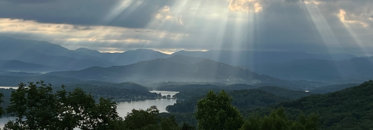 Dramatic sunbeams breaking through storm clouds over Lake Chatuge and the Blue Ridge Mountains.