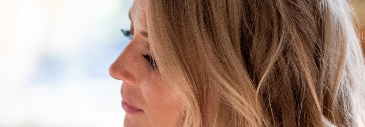 Side profile of a blonde woman looking down thoughtfully with a soft, blurred background.