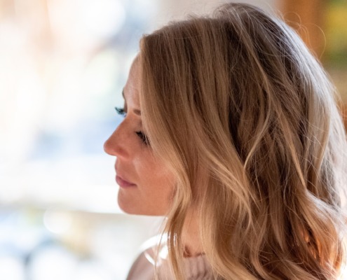 Side profile of a blonde woman looking down thoughtfully with a soft, blurred background.