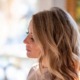 Side profile of a blonde woman looking down thoughtfully with a soft, blurred background.