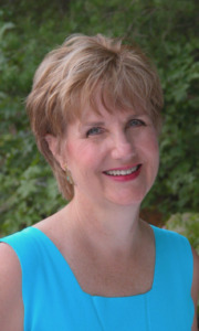 Benita A. Esposito, Licensed Professional Counselor and Spiritual Counselor for highly sensitive people, smiling warmly in a professional studio portrait set in a lush green garden.