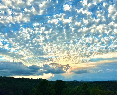Expansive blue sky filled with textured white clouds, symbolizing the neural expansion achieved at HSP Breathwork Retreats.