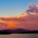 A panoramic sunset over Lake Chatuge with a full moon shining above vibrant pink and orange clouds.