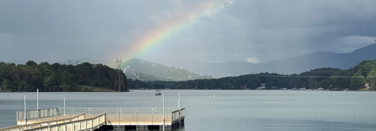 A vibrant rainbow breaking through storm clouds over Lake Chatuge in Young Harris, Georgia.