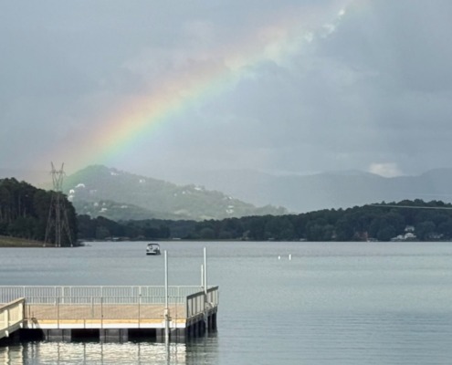 A vibrant rainbow breaking through storm clouds over Lake Chatuge in Young Harris, Georgia.