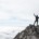 A man standing on a rocky mountain summit above a sea of clouds with one arm raised in surrender and worship, symbolizing emotional healing, trauma recovery, and spiritual liberation for a highly sensitive person.