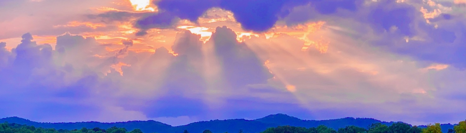 Sunbeams breaking through purple and gold clouds over the Blue Ridge Mountains in Young Harris, Georgia.