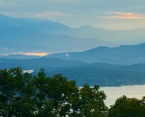 A scenic, peaceful view of the misty Blue Ridge Mountains and Lake Chatuge at dawn, captured by Benita A. Esposito to evoke emotional healing, calmness, and stillness for highly sensitive introverts.
